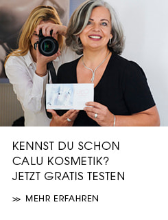 Frau Fischer von Calu lächelt in die Kamera und hält eine Calu Kosmetik-Produktbox in den Händen, während im Hintergrund eine blonde Fotografin ein Foto macht. Text im unteren Bereich: 'Kennst du schon Calu Kosmetik? Jetzt gratis testen >> Mehr erfahren'."