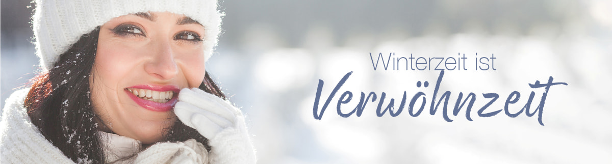 Lächelnde Frau in Winterkleidung mit Mütze und Handschuhen, hält sich die Hand an den Mund; Text: „Winterzeit ist Verwöhnzeit“.