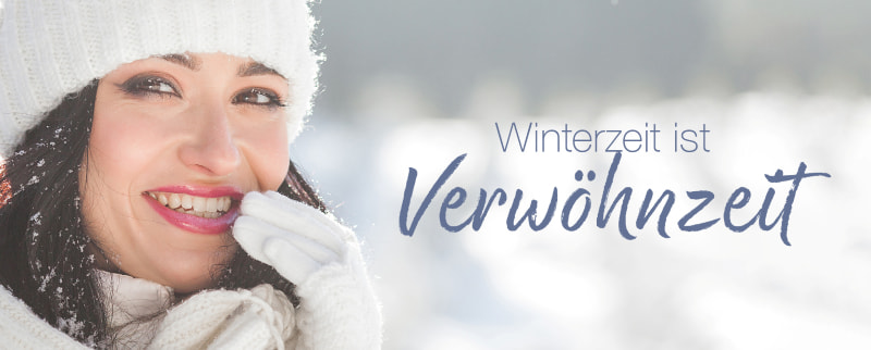 Lächelnde Frau in Winterkleidung mit Mütze und Handschuhen, hält sich die Hand an den Mund; Text: „Winterzeit ist Verwöhnzeit“.